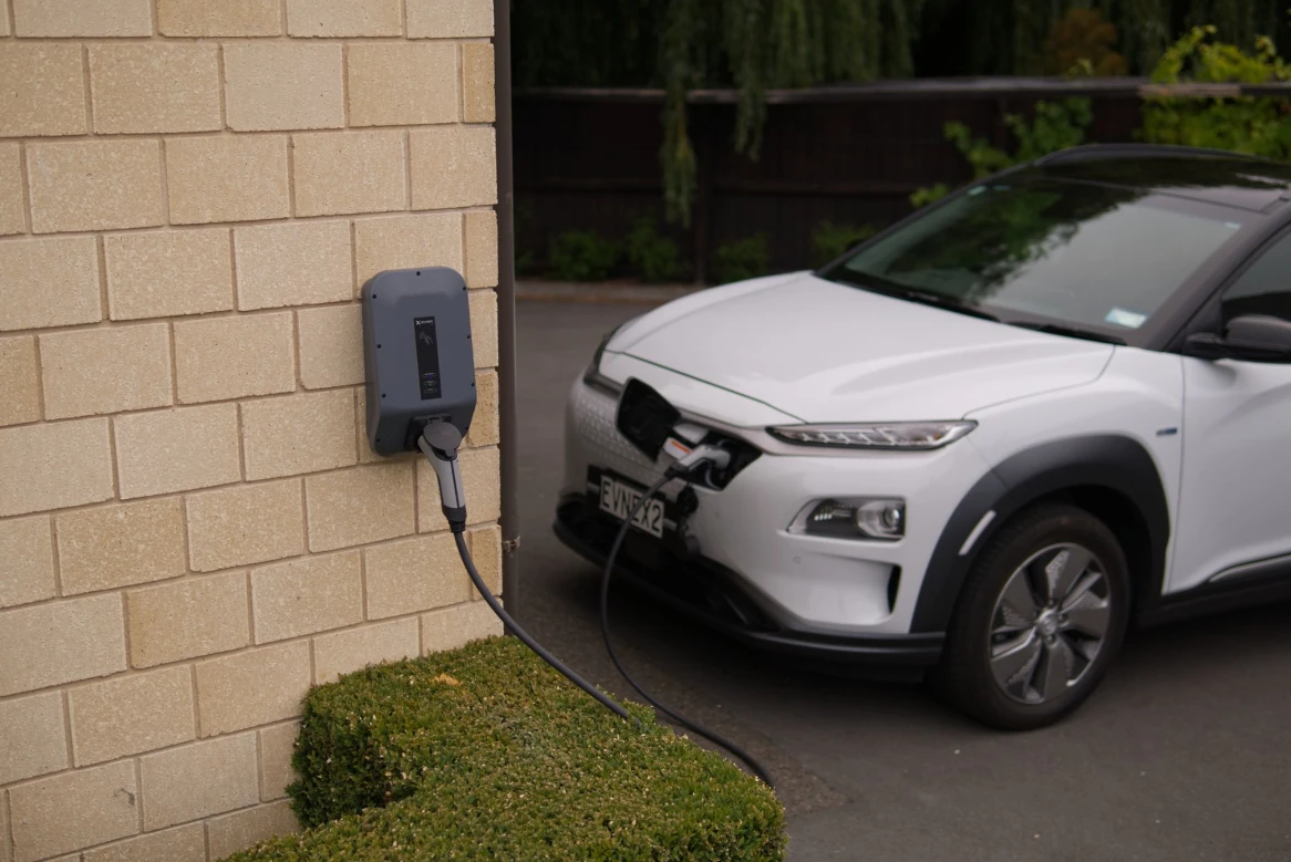 A car parked in a driveway connected to a home EV charger installed on a house