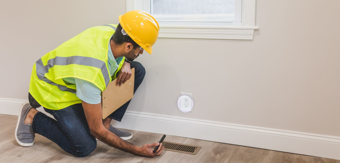 A home inspector inspecting an outlet below a window