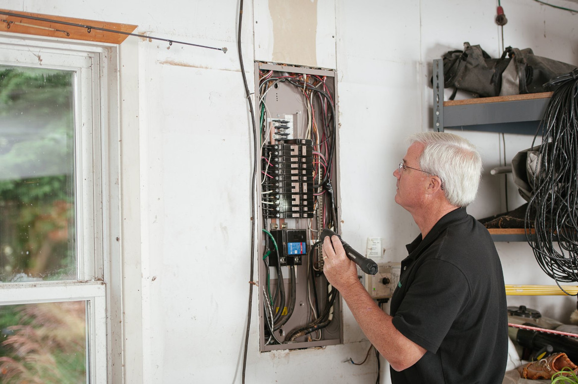 An electrician inspecting a home electrical panel